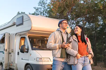 Urlaubsfahrt geschützt durch die Wohnmobilversicherung Pärchen steht vor dem Wohnmobil